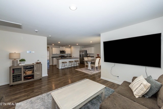 living area with dark wood-style floors, recessed lighting, visible vents, and baseboards