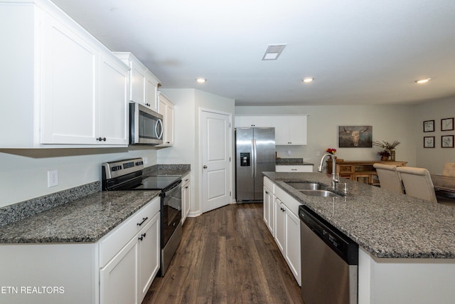 kitchen featuring dark wood finished floors, white cabinets, an island with sink, appliances with stainless steel finishes, and a sink