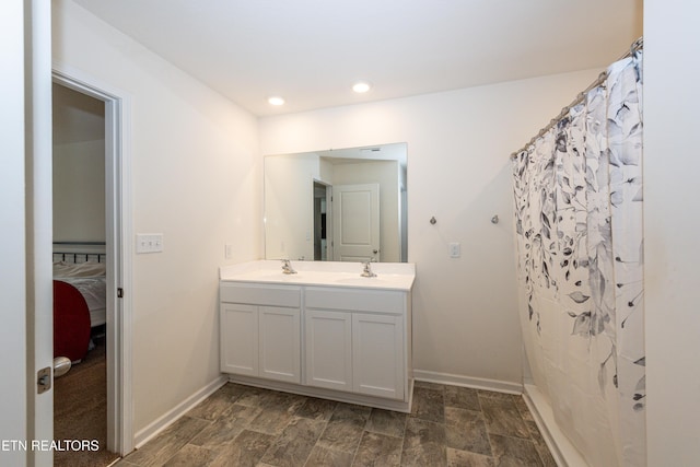 bathroom with double vanity, curtained shower, baseboards, and a sink