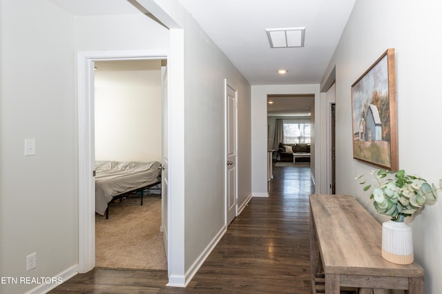 hallway featuring baseboards, visible vents, and dark wood finished floors