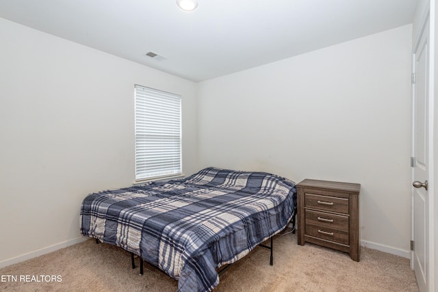 bedroom featuring baseboards, visible vents, and light colored carpet