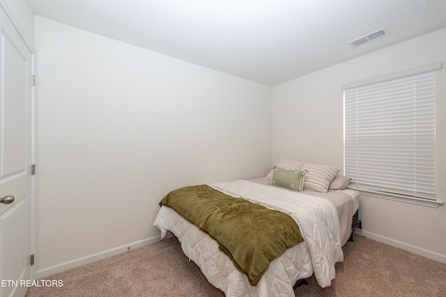 bedroom with baseboards, visible vents, and light colored carpet