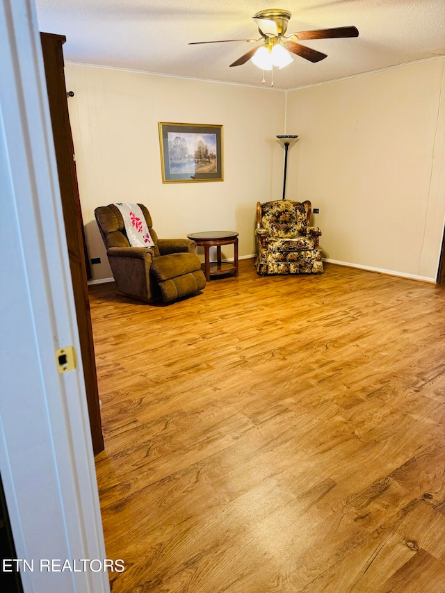 living area with ceiling fan, a textured ceiling, and light hardwood / wood-style flooring