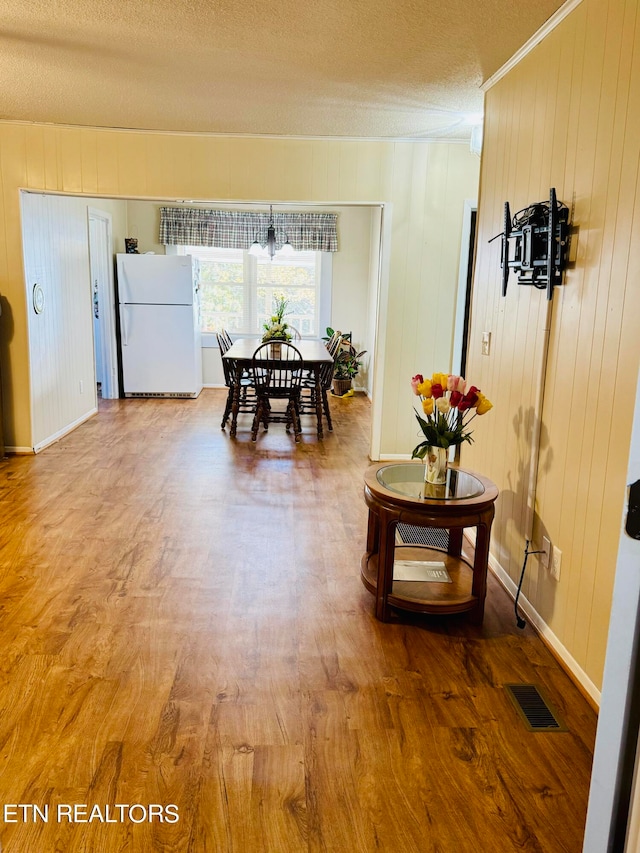 dining space featuring wood walls, a textured ceiling, and wood-type flooring