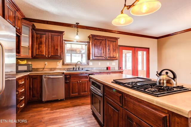 kitchen with sink, hanging light fixtures, hardwood / wood-style floors, ornamental molding, and black appliances