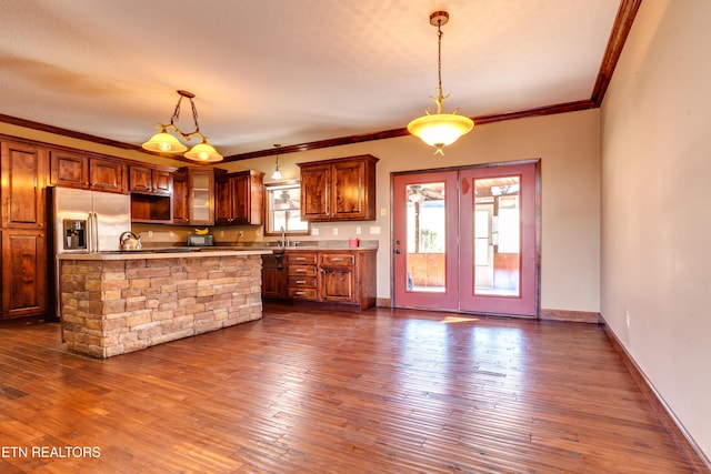 kitchen with dark hardwood / wood-style floors, ornamental molding, stainless steel fridge, and hanging light fixtures