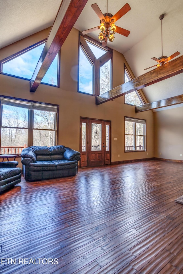 unfurnished living room with a towering ceiling, dark wood-type flooring, and ceiling fan