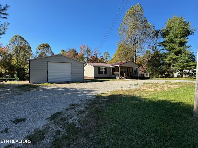 ranch-style home with a garage, a front lawn, an outbuilding, and a porch