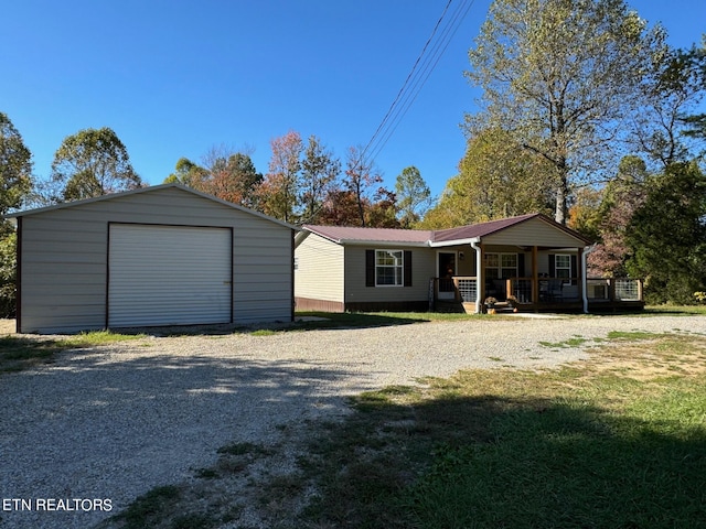 view of front of house with covered porch, a front yard, an outbuilding, and a garage