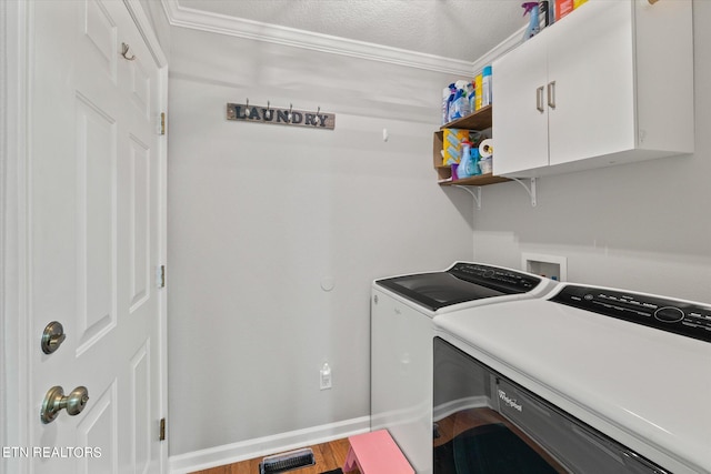 washroom featuring separate washer and dryer, a textured ceiling, crown molding, hardwood / wood-style flooring, and cabinets