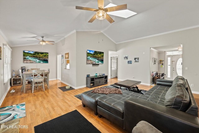 living room with light hardwood / wood-style floors, ornamental molding, lofted ceiling with skylight, and ceiling fan