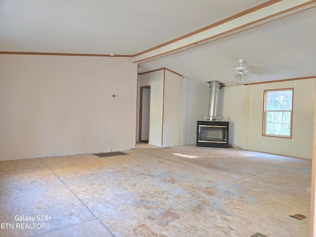 unfurnished living room with ceiling fan, crown molding, and a wood stove