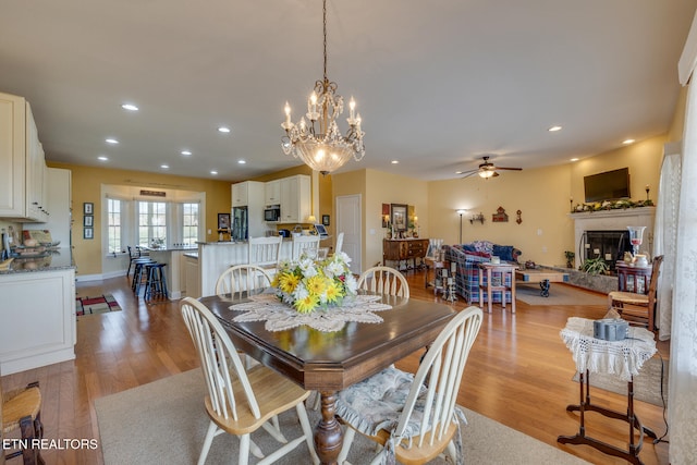 dining space featuring light hardwood / wood-style floors and ceiling fan with notable chandelier