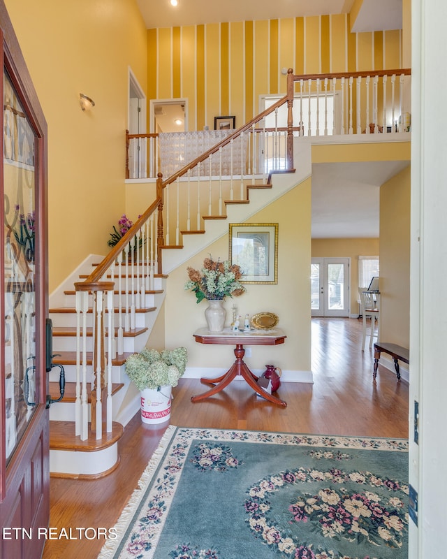 interior space featuring a towering ceiling, french doors, and hardwood / wood-style floors