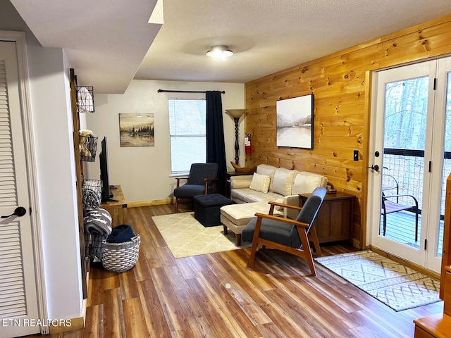 living room with wood walls, hardwood / wood-style floors, a healthy amount of sunlight, and a textured ceiling