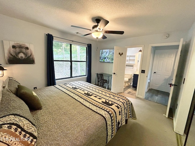 carpeted bedroom with a textured ceiling, ensuite bathroom, and ceiling fan