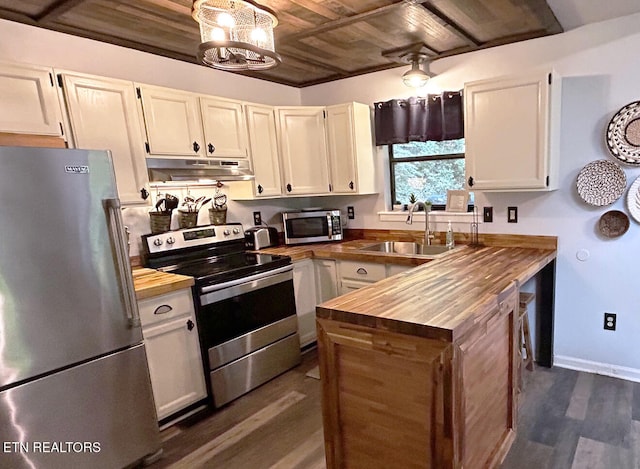 kitchen with dark wood-type flooring, appliances with stainless steel finishes, white cabinetry, and butcher block counters