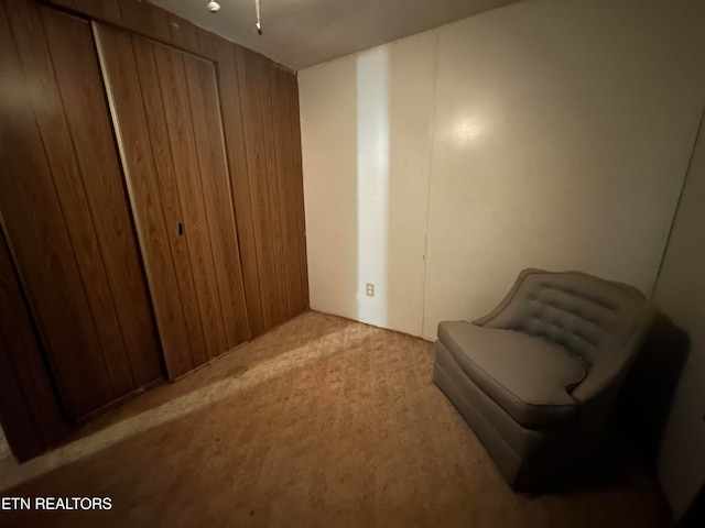 sitting room with wooden walls and light colored carpet