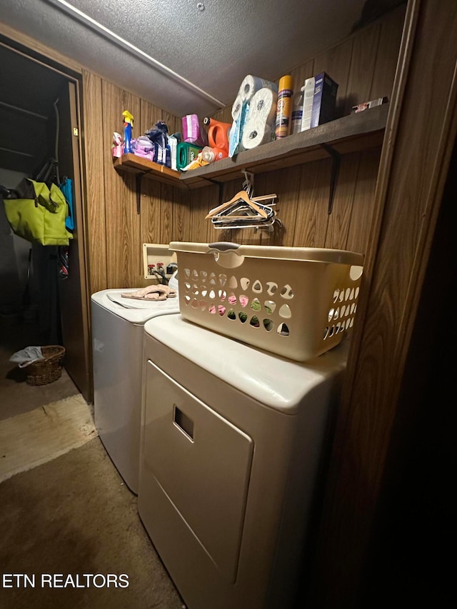 washroom featuring washing machine and clothes dryer, a textured ceiling, and wood walls