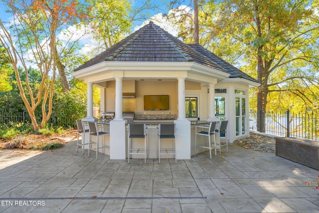 view of patio / terrace featuring an outdoor bar, exterior kitchen, a gazebo, and a grill