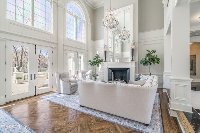 living room featuring ornamental molding, dark parquet floors, a high ceiling, and decorative columns