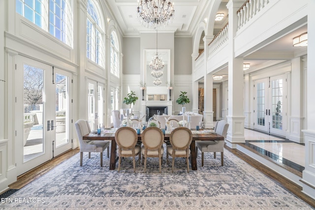 dining space with french doors, hardwood / wood-style flooring, a wealth of natural light, and a high ceiling