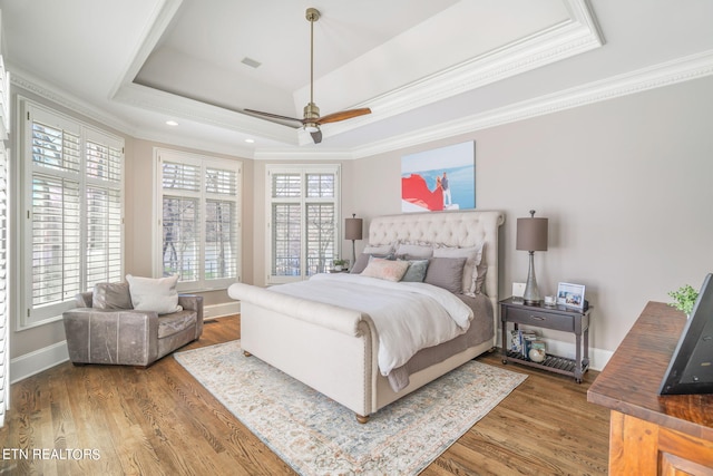 bedroom with ceiling fan, ornamental molding, a tray ceiling, and hardwood / wood-style floors