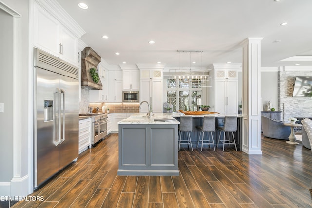 kitchen with white cabinets, dark hardwood / wood-style floors, custom range hood, and built in appliances