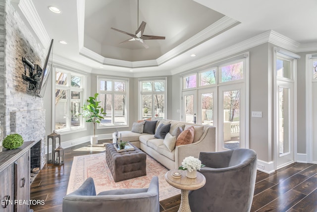 sunroom with a stone fireplace, a tray ceiling, and ceiling fan