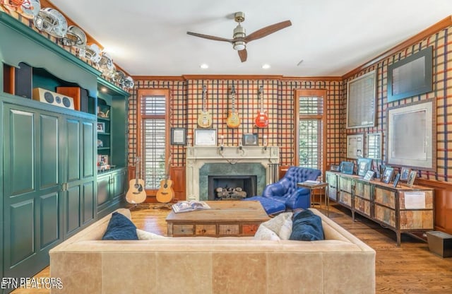 living room featuring hardwood / wood-style flooring, a healthy amount of sunlight, a premium fireplace, and crown molding