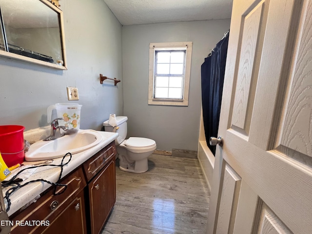 full bathroom featuring a textured ceiling, shower / bath combination with curtain, toilet, vanity, and hardwood / wood-style flooring