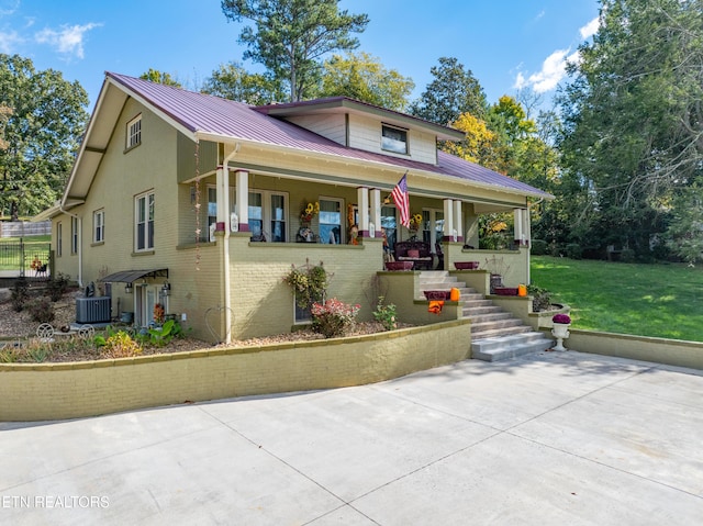 view of front facade with a front yard, a porch, and cooling unit