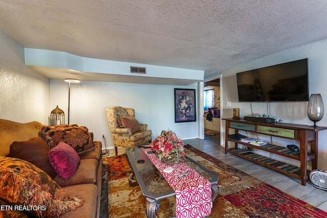 living room with wood-type flooring and a textured ceiling