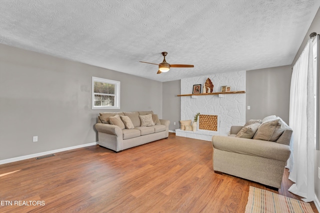 living room with hardwood / wood-style floors, a textured ceiling, and ceiling fan