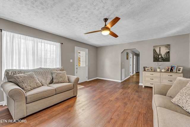 living room featuring a textured ceiling, dark hardwood / wood-style floors, and ceiling fan