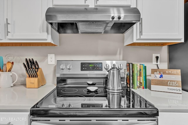 kitchen with white cabinetry, exhaust hood, and stainless steel range with electric cooktop