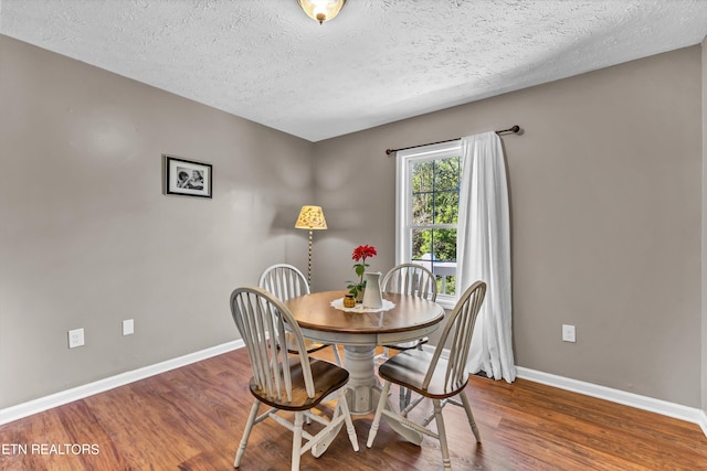 dining space with hardwood / wood-style floors and a textured ceiling