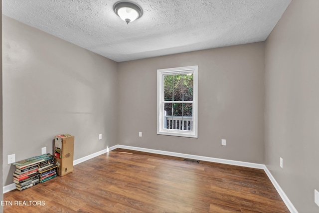 empty room with a textured ceiling and hardwood / wood-style flooring