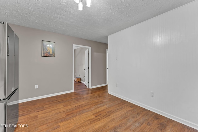 spare room featuring wood-type flooring and a textured ceiling