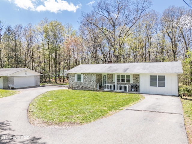 ranch-style house with a garage, a front lawn, an outbuilding, and a porch