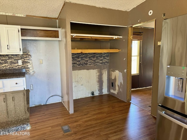 kitchen featuring stainless steel fridge with ice dispenser, white cabinetry, a textured ceiling, dark stone counters, and dark wood-type flooring