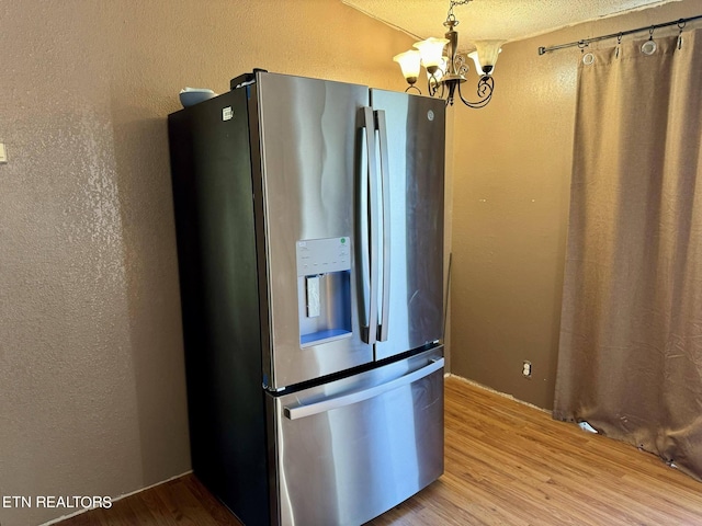 kitchen with an inviting chandelier, light hardwood / wood-style flooring, stainless steel fridge, and a textured ceiling