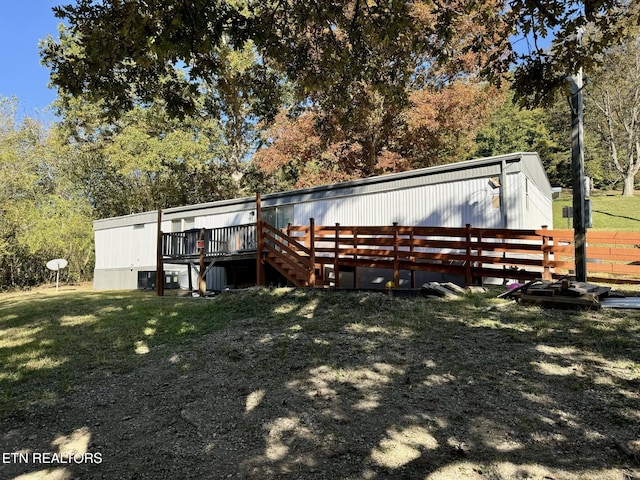 back of property featuring a deck and a lawn