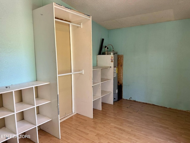 unfurnished bedroom with light hardwood / wood-style floors, water heater, and a textured ceiling