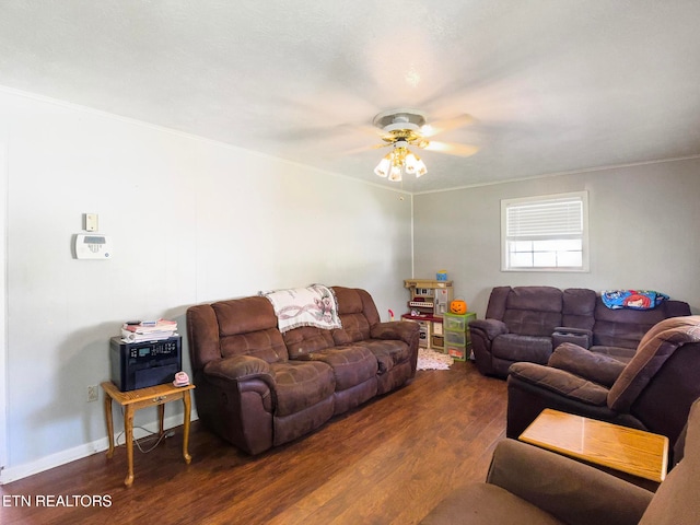 living room with dark wood-type flooring, crown molding, and ceiling fan