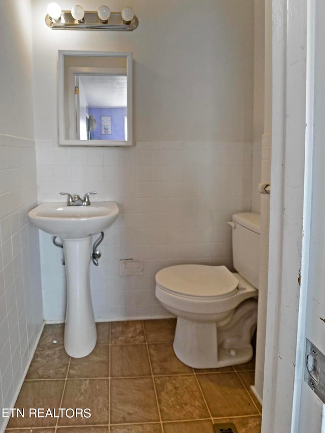 bathroom with tile walls, toilet, and tile patterned flooring