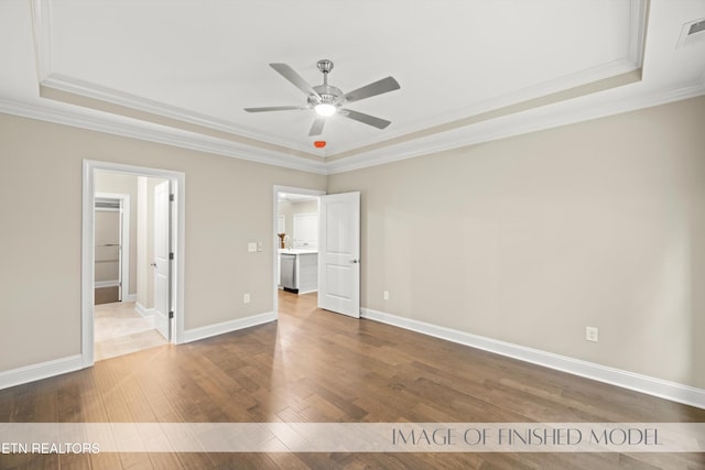 unfurnished bedroom with a raised ceiling, ceiling fan, connected bathroom, wood-type flooring, and crown molding