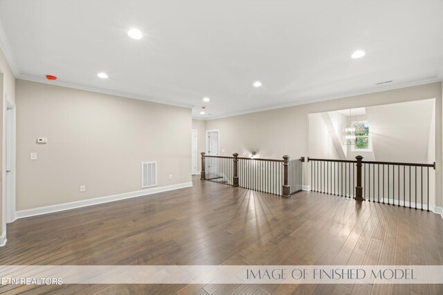 spare room featuring crown molding, dark hardwood / wood-style flooring, and a chandelier