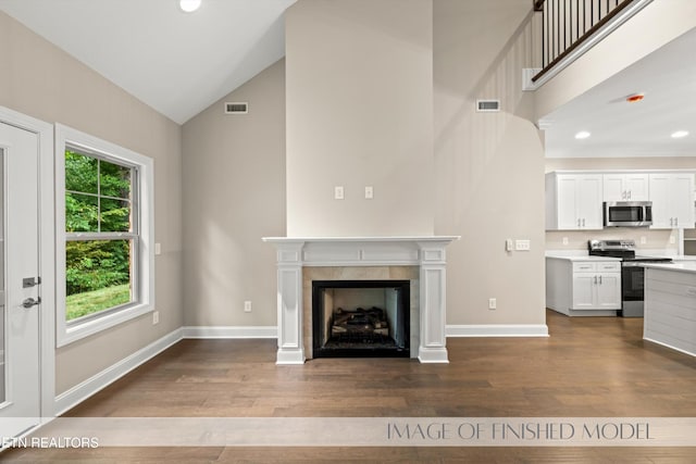 unfurnished living room with a tiled fireplace, light hardwood / wood-style floors, and lofted ceiling