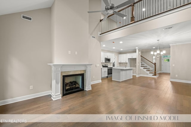 unfurnished living room with dark wood-type flooring, a fireplace, a high ceiling, and sink